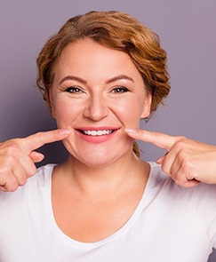 smiling woman pointing to her gums after Arestin antibiotic treatment