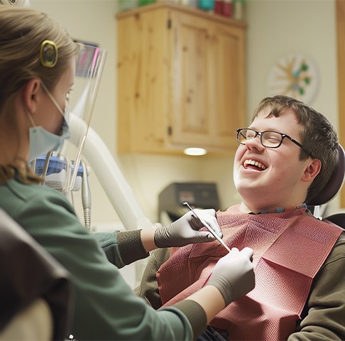 Boy with glasses smiling as he visits his dentist for special needs dentistry in Jeffersonville