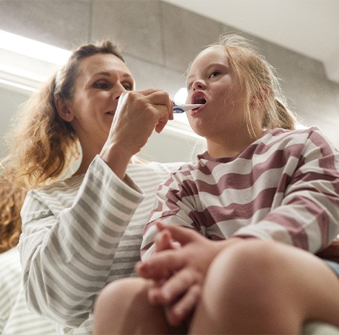Caregiver brushing teeth of a child with physical or intellectual disability in Jeffersonville
