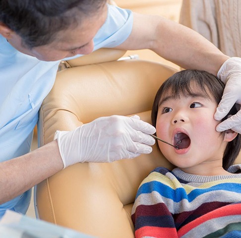 Young boy with his mouth open as his dentist looks at his teeth