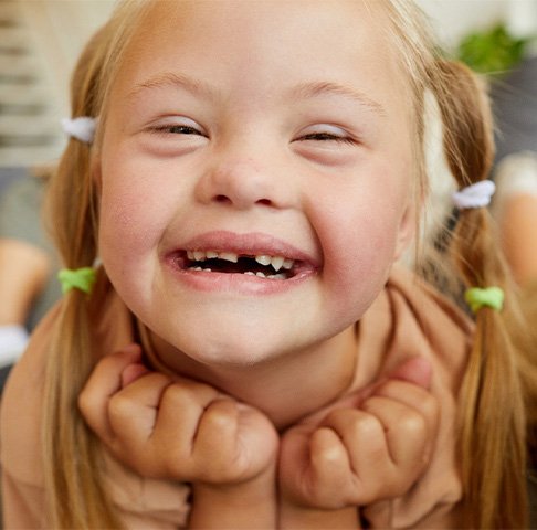 Child with an intellectual or physical disability in Jeffersonville lounging on couch, smiling, and missing a tooth