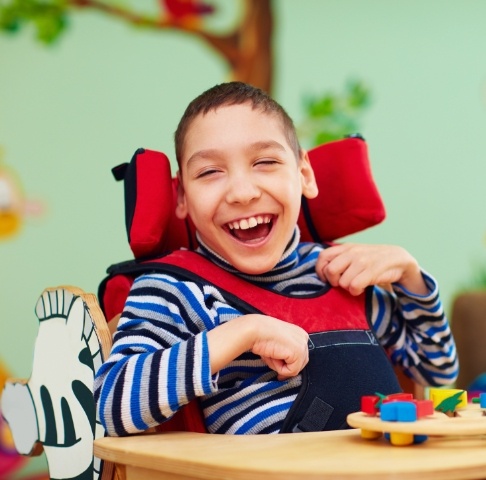 Child in wheelchair laughing after special needs dentistry visit