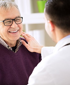 older patient smiling at his dentist after emergency dental care