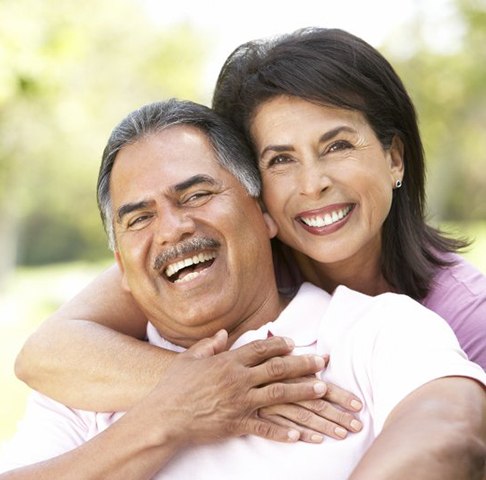Man and woman smiling and laughing outside with beautiful teeth