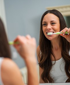 Woman with long brown hair brushing her dental implant