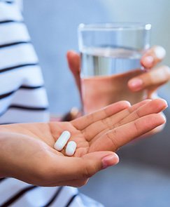 Patient holding pain medication and glass of water