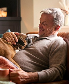 Man relaxing at home and petting his dog