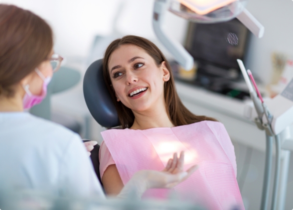 Smiling woman in dental chair talking to team member