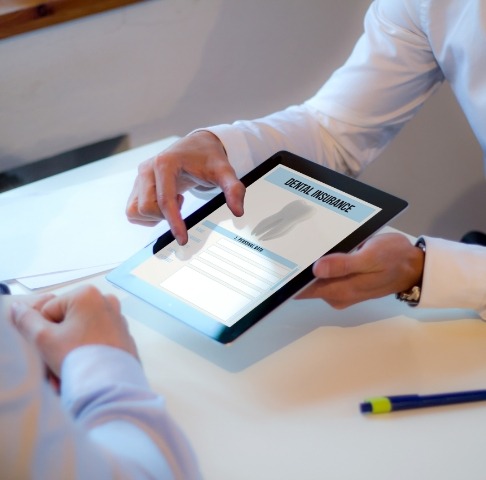 Dental team member and patient reviewing dental insurance forms together