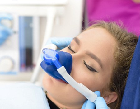 Woman relaxing in dental chair with mask administering nitrous oxide sedation