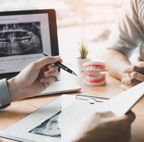 Closeup of dentist with paperwork explaining pre-determinations to patient 