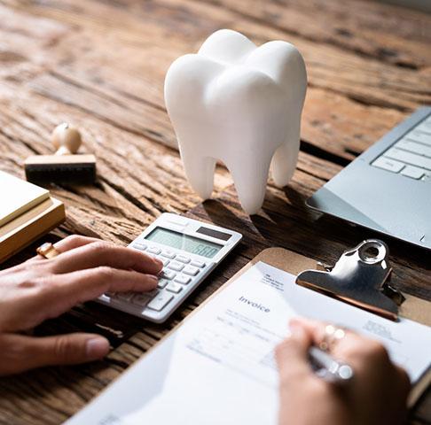 Closeup of a dentist filling out dental pre-determination paperwork with model tooth