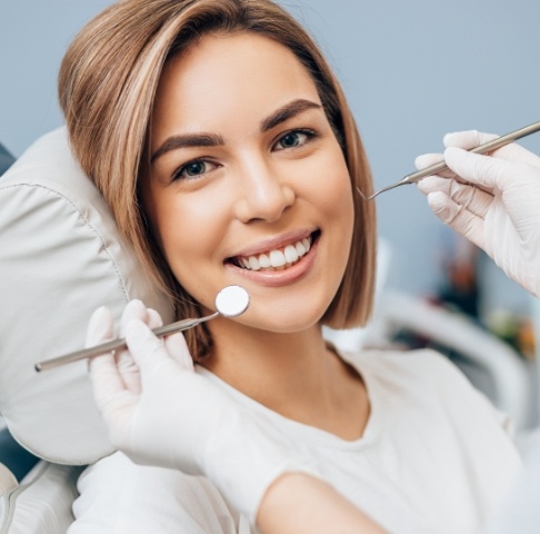 Smiling woman receiving dental checkup and teeth cleaning during preventive dentistry visit
